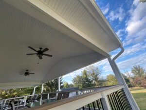 "A spacious outdoor patio featuring two ceiling fans and a white beadboard ceiling, offering a comfortable and stylish outdoor living area.